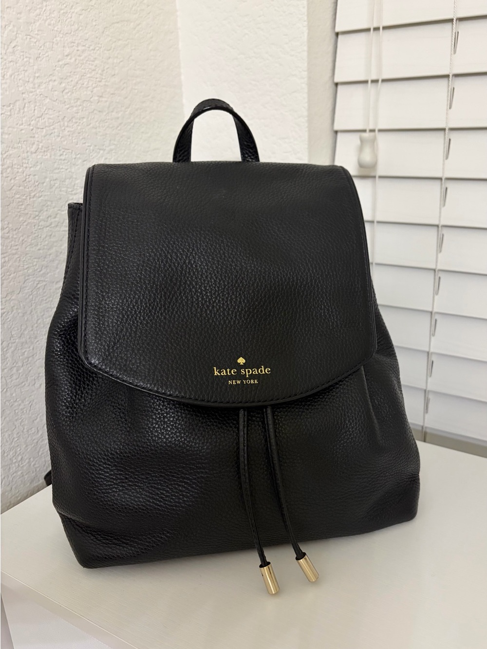 kate spade black pebble leather backpack with gold accents.